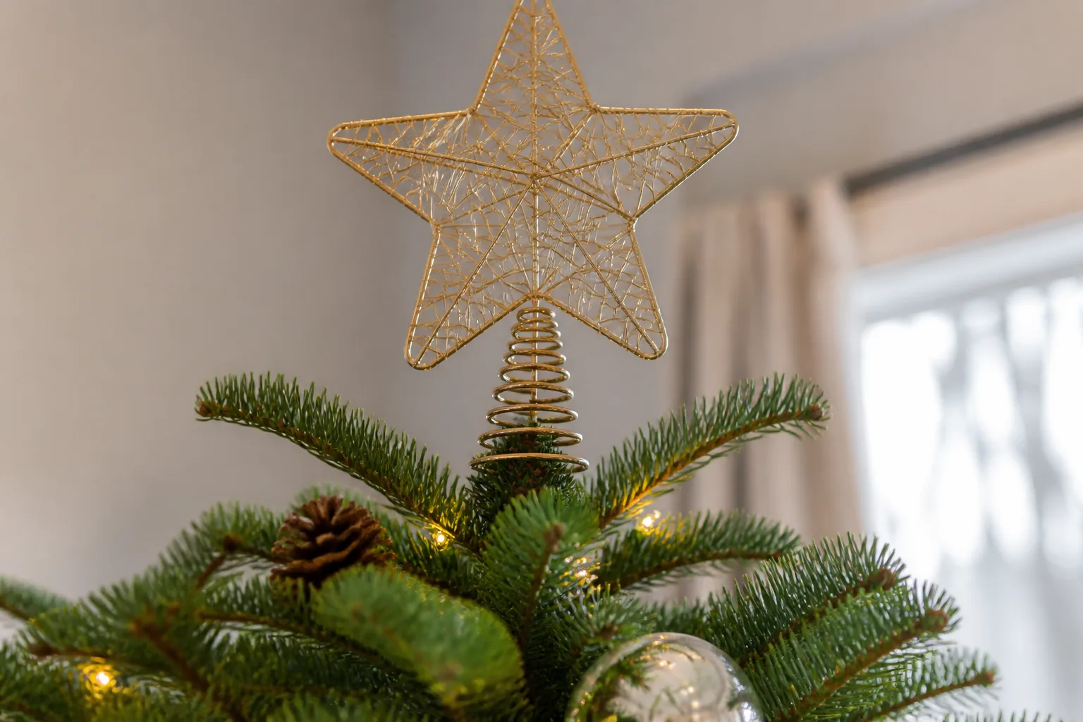 A star tree topper secured on the central stem above the upper branches