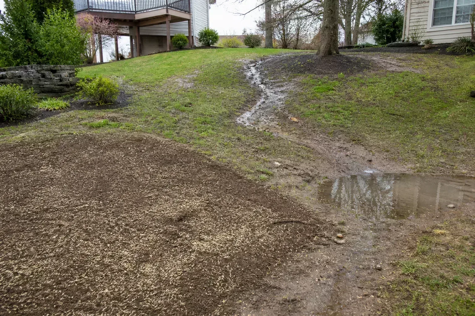 A runoff channel cutting through exposed soil on a residential slope.