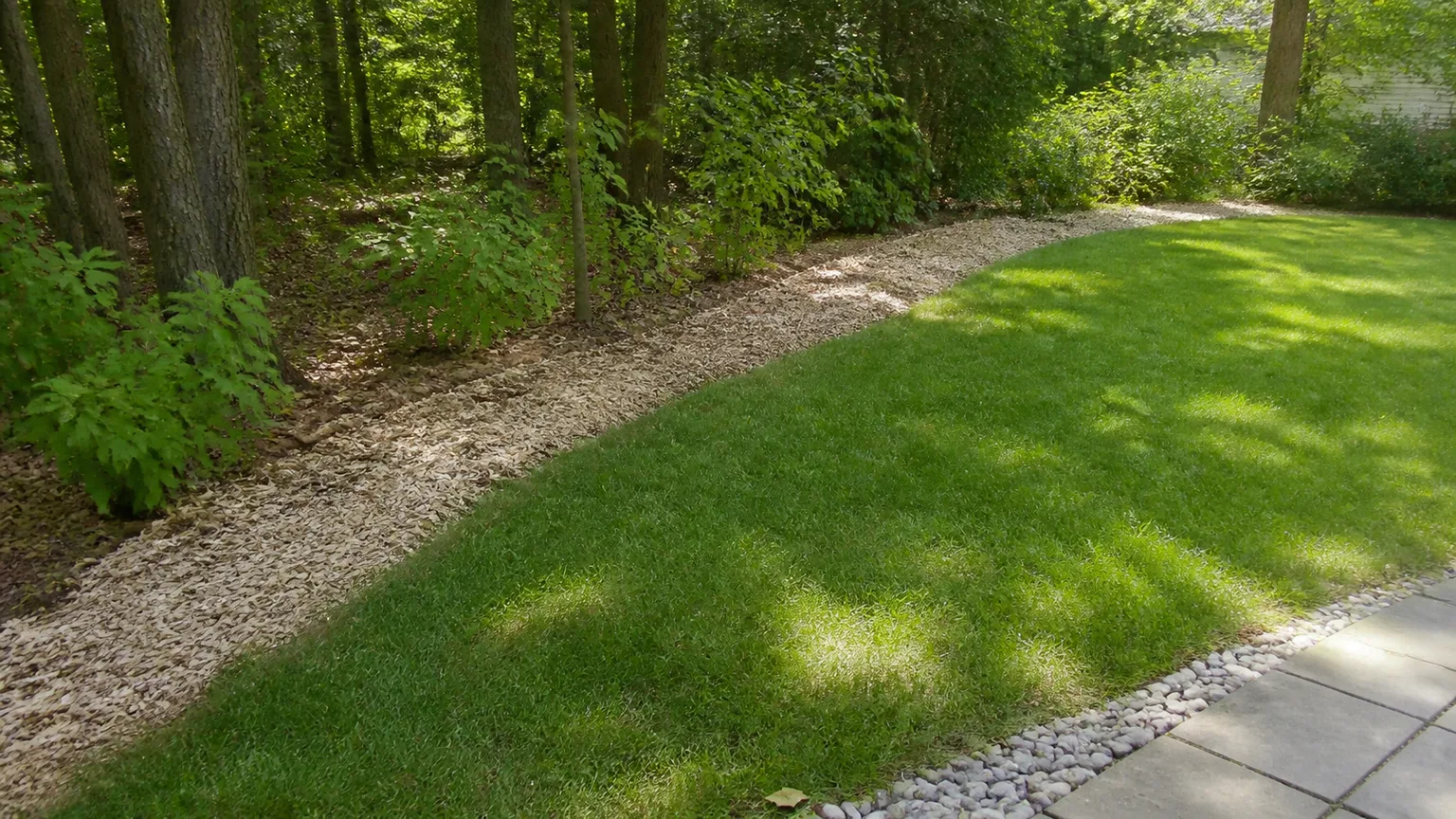 A garden border using ground cover, mulch, and stone edging