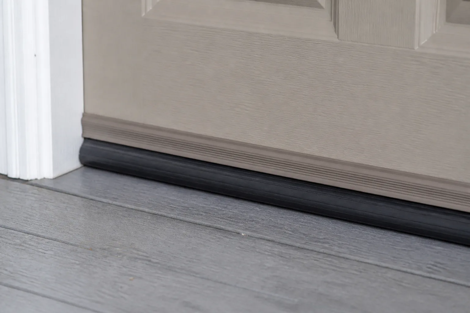 Fresh door weatherstripping being aligned along an exterior entry threshold