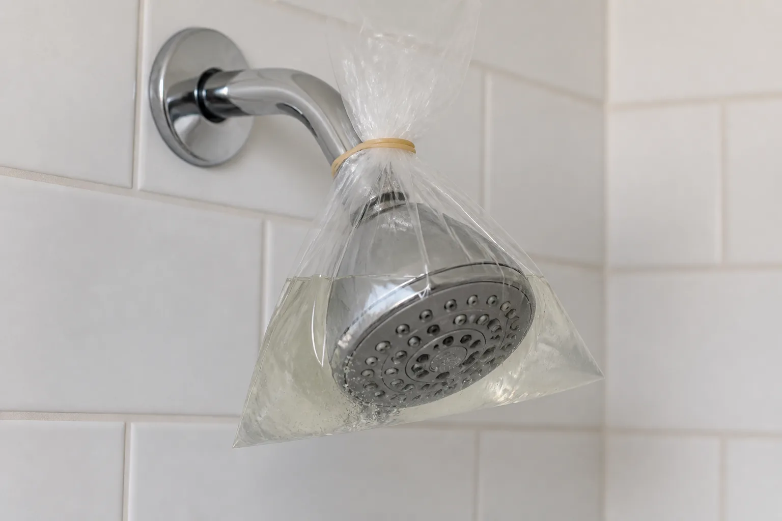 A vinegar soak bag covering a showerhead for controlled mineral and residue cleaning