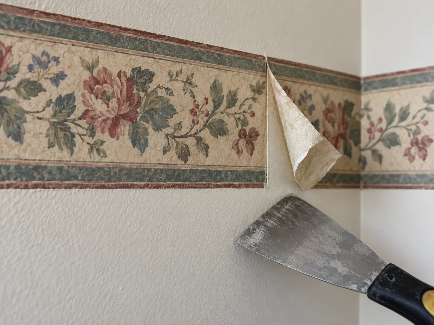 A small corner of wallpaper border lifted to test whether it will peel dry