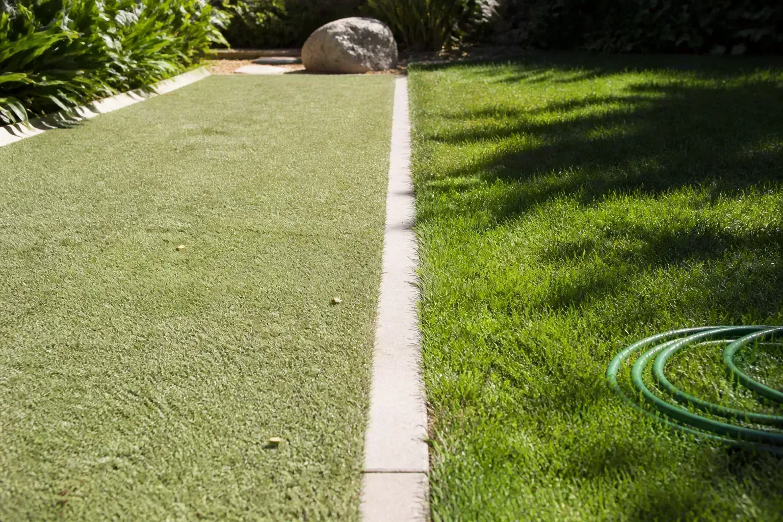 Artificial grass in a sunny yard beside a shaded section